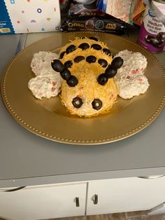 a yellow plate topped with a cake covered in frosting and black olives on top of a counter