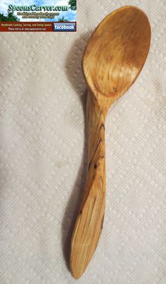 a wooden spoon sitting on top of a white cloth covered table next to a business card