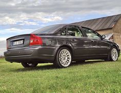 a black car parked in front of a house on the side of a field with grass