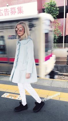 a woman is walking down the street in front of a train