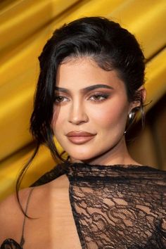 a close up of a person wearing a black dress with sheer lace on it and large hoop earrings