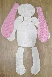 a paper doll made to look like a bunny with pink ears and tail sitting on top of a wooden floor