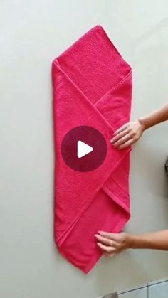 a woman is holding a pink towel on the wall