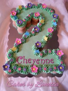 a birthday cake with flowers and cupcakes on it that says 2 cheyene