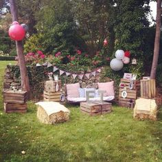 an outdoor party with hay bales, balloons and wooden crates on the grass in front of some trees