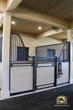 the inside of a horse stable with an iron gate and black railings on each side