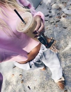 a woman in pink shirt and white pants holding a cell phone next to her leg