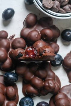 a spoon full of chocolate covered cherries next to blueberries and chocolate coated almonds