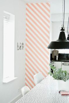 a dining room table and chairs in front of a wall with vertical stripes on it