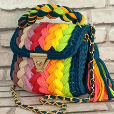 multicolored braided purse sitting on top of a wooden table next to a brick wall