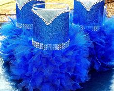 two blue princess crowns sitting on top of a table next to each other with tulle