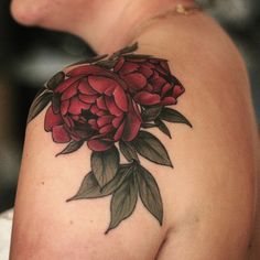 the back of a woman's shoulder with flowers on it and leaves around her arm