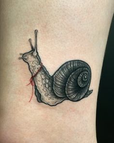 a small tattoo of a snail on the side of a woman's leg,