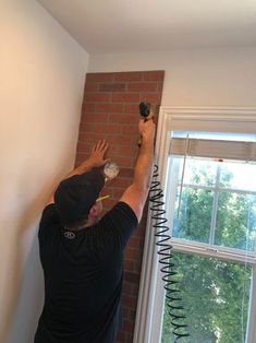 a man working on a brick wall with a clock in his hand and wires attached to it