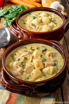 two brown bowls filled with chicken and dumpling soup on top of a wooden table