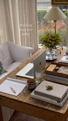 a wooden table topped with books next to a laptop computer on top of a desk