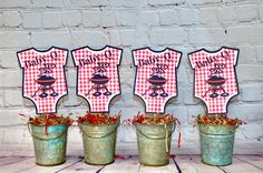 four pails with red and white gingham shirts on them sitting in front of a brick wall