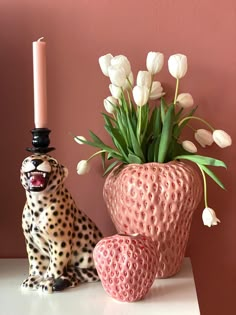 a leopard figurine next to a vase with tulips and a candle