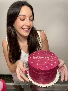 a woman holding a birthday cake with hearts on it