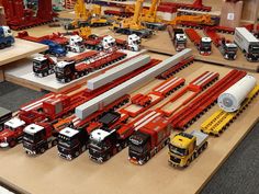 many toy trucks and cars are on display in a building area with construction equipment around them