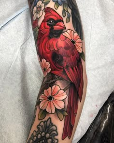 a red bird with flowers on it's arm