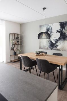 a dining room table with chairs and a painting on the wall