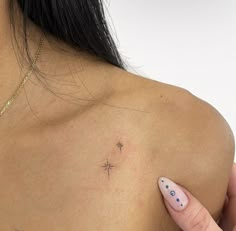 a woman with a cross tattoo on her left shoulder, and a small star in the middle