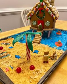 a gingerbread house made out of sand with candy canes and candies on the table