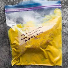 a yellow bag with writing on it sitting on top of a cement floor next to a wall