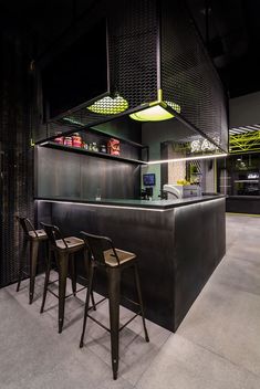 a bar with three stools in front of it and some lights hanging from the ceiling