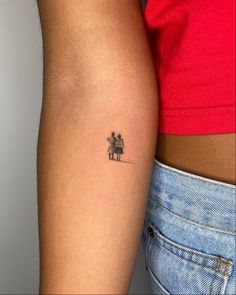 a small tattoo on the arm of a woman's left arm, with an image of two people holding each other