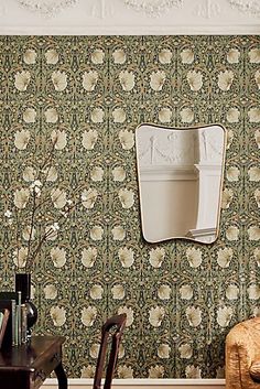 a chair and table in front of a wall papered with white flowers on it