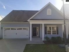 a gray house with white trim and two garages on the front door is shown