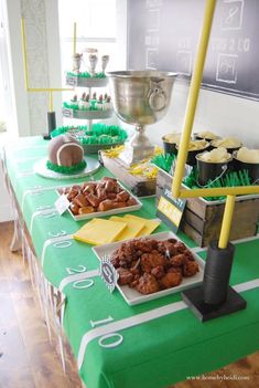 a green table topped with lots of food and cupcakes on top of it