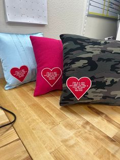 three pillows with hearts on them sitting on a table