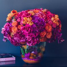 a vase filled with lots of colorful flowers on top of a table next to a book