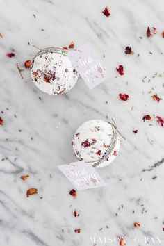 two cupcakes sitting on top of a white marble table covered in rose petals