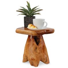 a small wooden table topped with a cup and plate next to a potted plant