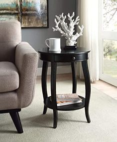 a small table with magazines and a vase on it next to a couch in a living room