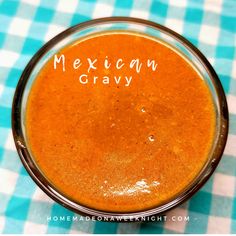 mexican gravy in a glass bowl on a checkered tablecloth with the words, mexican gravy