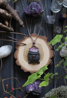 a necklace with a purple stone in the middle on top of a piece of wood