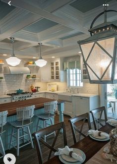 an open kitchen and dining room area with white cabinets, wood table and blue chairs