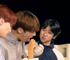 two men and a woman are eating food in front of a man with his mouth open