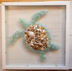 a sea turtle in a white frame with shells and starfish on it's back