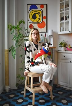 a woman sitting in a chair holding a dog