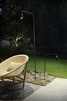 a chair sitting in the grass next to a lamp on a pole and some lights