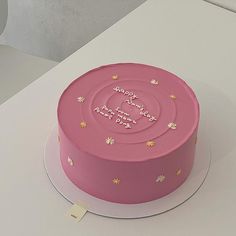 a pink cake sitting on top of a white table