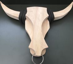 a wooden bull's head with black rope around it on a gray surface,