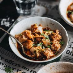 two bowls filled with food sitting on top of a table next to glasses and silverware