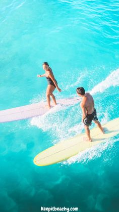 two people on surfboards in the ocean with one person standing up and another sitting down